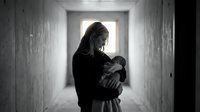 Young mother holding newborn baby in hospital corridor with dramatic lighting and emotional atmosphere for healthcare and maternity concepts.