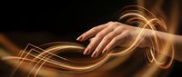 Female hand with manicured nails interacting with glowing golden light waves and swirling energy effects against dark background for creative and technology concepts.