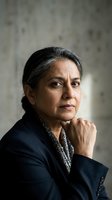 Mature South Asian businesswoman in dark suit with thoughtful expression and hand on chin in professional portrait for corporate leadership content.