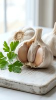 Fresh garlic bulbs with parsley on rustic wooden cutting board in bright kitchen setting for culinary cooking and food preparation concepts.