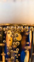 Sparkling bubbles rising in golden fizzy drink with warm bokeh lights creating festive atmosphere for celebration and party concepts.