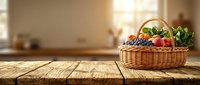 Wicker basket filled with fresh produce including blueberries, tomatoes and leafy greens sitting on wooden table with sunlit kitchen background for food and cooking content.