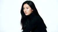 Young Asian woman with long black hair wearing dark clothing against white background for portrait photography and fashion projects.