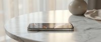 Modern smartphone lying flat on a white marble table in a bright, minimalist interior with soft natural light and neutral decor.