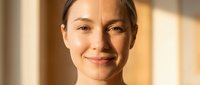 Young woman face showing aging process with wrinkles and smooth skin comparison in warm natural light for skincare and beauty treatment concepts.
