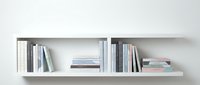 Modern white floating wall shelves with organized books and magazines for contemporary home office or living room interior design.