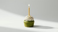 Pistachio cupcake with cream frosting and single lit birthday candle on neutral background for celebration and bakery designs.