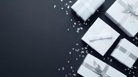 Elegant white gift boxes with silver ribbons and bows arranged on dark background with scattered pearls for luxury holiday celebration and special occasions.