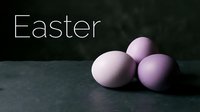 Three pastel purple Easter eggs on dark stone surface with elegant Easter text, moody holiday greeting card composition.