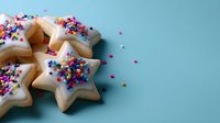 Star-shaped sugar cookies with white icing and colorful sprinkles on turquoise background, perfect for holiday baking and festive celebrations.