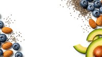 Healthy superfood ingredients with fresh blueberries, avocado slices, almonds and chia seeds arranged on white background for nutrition concepts.