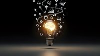 Glowing light bulb with business icons and charts floating above representing innovation, creativity, and strategic planning for corporate success.