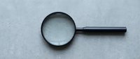 Magnifying glass with black handle on gray textured surface for research, investigation, and detailed examination projects.