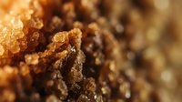 Brown sugar crystals in macro close-up with warm golden lighting, showing texture and granules for food, baking, and culinary content.