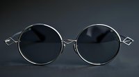 Round silver metal sunglasses with dark lenses and decorative geometric temple details on black background, fashion accessory for modern style and sun protection.