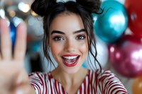 Young woman taking selfie with excited expression at birthday party with colorful balloons in background for social media and celebration content.