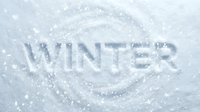 Word WINTER carved into fresh white snow surface with swirling patterns and falling snowflakes, creating a seasonal cold weather concept.