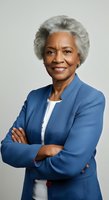 Senior African American woman with gray hair wearing blue blazer and white top, arms crossed, smiling at camera against neutral background for corporate and business portraits.