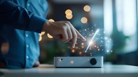 Finger touching holographic projection above modern device with glowing particles and bokeh lights in dark room, showcasing futuristic technology interface.