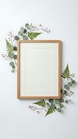 Wooden frame with white mat surrounded by fresh eucalyptus leaves, green ferns, and burgundy berries on neutral background. Perfect for home decor, botanical styling, and gallery wall displays.