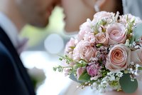 Delicate blush pink roses and tiny white flowers create romantic wedding bouquet with soft bokeh background, captured in intimate moment during ceremony.
