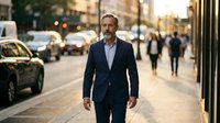 Confident middle-aged Caucasian businessman walking on a busy city street in a navy suit, exuding leadership and success in an urban setting.