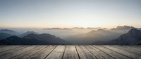 Wooden deck platform overlooking misty mountain landscape at sunrise, suitable for product placement, travel, and lifestyle design projects.