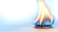 Bright orange flame burning on blue gas burner against soft blurred background, demonstrating energy consumption and heating concepts.