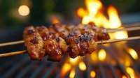 Grilled meat skewers with caramelized glaze cooking over open flames, barbecue food preparation for outdoor dining and summer gatherings.