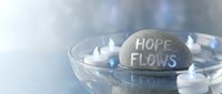 Hope flows engraved stone with floating candles in glass bowl creating peaceful meditation atmosphere for wellness and spiritual healing practices.