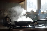 Steam rising from hot pan on gas stove in home kitchen, atmospheric cooking scene with natural window light perfect for food blogs and culinary content.