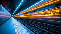 Long exposure shot of subway platform with dynamic light trails creating futuristic motion effect, empty underground station with blue and orange streaks.