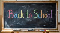 Back to School written in colorful chalk on black chalkboard with wooden frame and chalk pieces, education concept for classroom learning and academic year start.