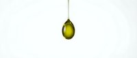 Golden olive oil drop falling from spoon against clean white background for culinary and cooking applications.