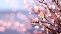 Glowing fairy lights wrapped around delicate branches create magical bokeh effect against soft pink and blue twilight background, festive winter mood.