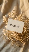 Thank you card resting on dried baby's breath flowers against beige linen, elegant boho aesthetic for weddings, events, and greeting designs.