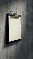 Empty clipboard with blank paper hanging on concrete wall for business planning and note-taking in modern office workspace.