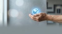Mature male hand holding glowing blue globe icon symbolizing global business, sustainability, and corporate social responsibility for web and marketing use.