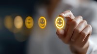 Hand drawing glowing yellow smiley face emoji in air with finger, digital customer satisfaction and feedback concept on blurred background with bokeh lights.