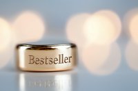 Golden ring with bestseller engraving on blurred bokeh background. Macro photography of jewelry piece reflects success and achievement in literature.
