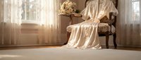 Elegant vintage armchair with cream silk fabric drape in sunlit room with soft curtains and floral arrangement creating luxurious interior atmosphere.