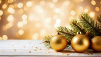 Golden Christmas ornaments with pine branches on white wooden surface against warm bokeh background for festive holiday designs.