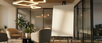 Modern office meeting room with contemporary furniture, glass partitions and warm LED lighting creating professional workspace atmosphere for business presentations.