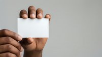 Male hand with dark skin tone holding blank white card against neutral background, suitable for business, identity, branding, and marketing mockup applications.