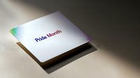 White paper card with rainbow holographic text reading Pride Month casting soft shadow on neutral surface, minimalist LGBTQ+ design element for pride celebrations.