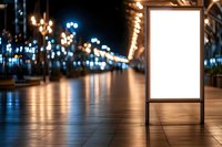 Blank illuminated advertising billboard mockup at night city street with bokeh lights and reflections on wet pavement. Empty display for marketing.