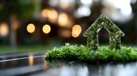 Small green moss house silhouette on natural background with bokeh lights creating magical atmosphere for environmental and sustainable living concepts.
