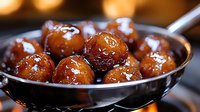 Glossy caramelized pearl onions in metallic spoon, glazed with sweet sauce for gourmet cooking and holiday side dishes.