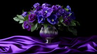 Purple roses and pansies in glass vase on dark background with flowing silk fabric creating dramatic luxury composition for romantic occasions.
