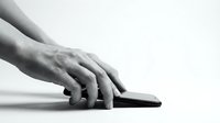 Close-up of male hands picking up a smartphone from a white surface, monochrome shot conveying technology and everyday mobile use.